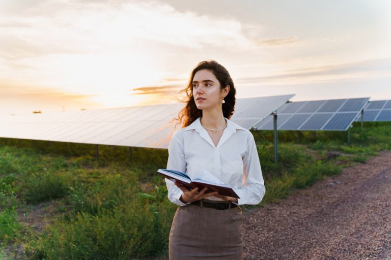 Woman reading book in front of solar panels